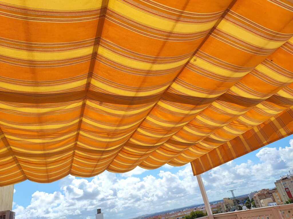 Toldo de lona a rayas naranjas visto desde debajo en Cádiz